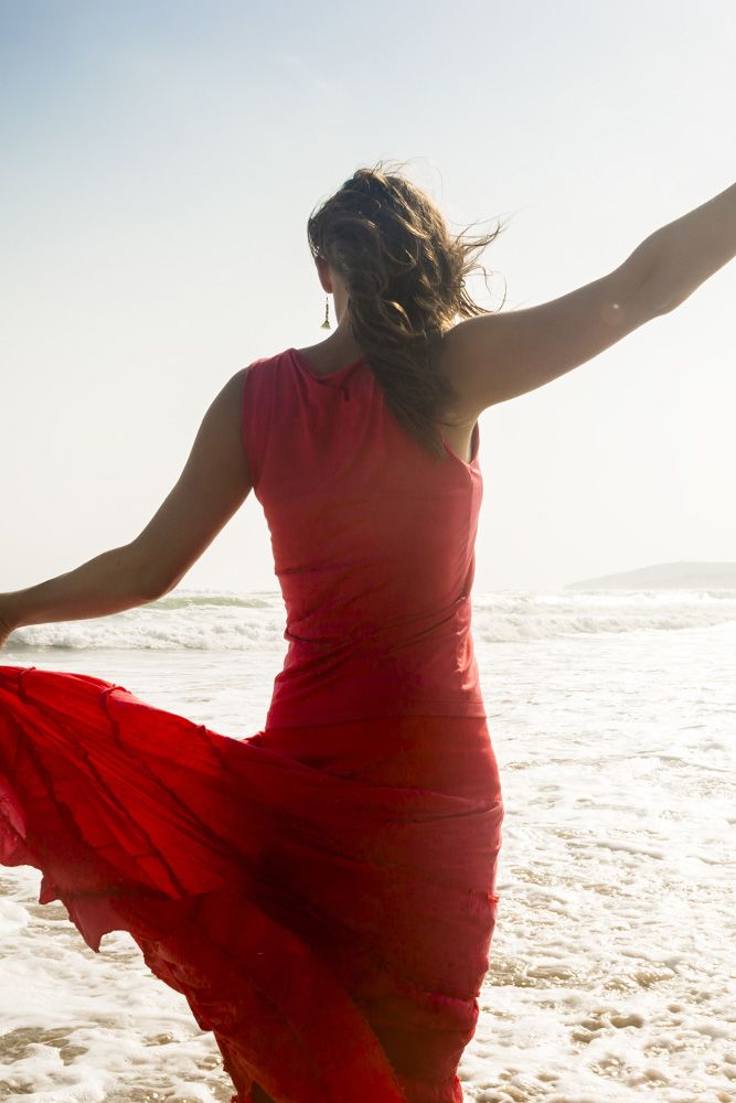 A woman in a red dress standing on the shore