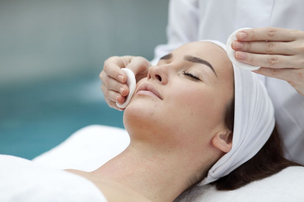Woman lying down with eyes closed receiving chemical peel